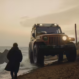 jeep coming out of the ocean while its owner waits