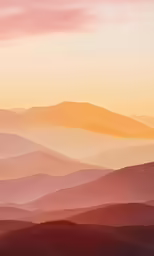 a beautiful sunset over the mountains with layers of mist