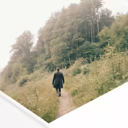there is a man walking on the trail in the field