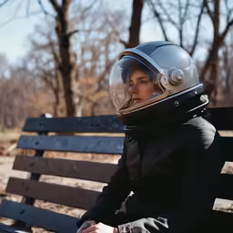 there is a person sitting on the bench wearing a helmet