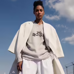 a woman in white clothes wearing an oversized coat