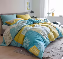 an open room with a bed, two pillows and a throw blanket
