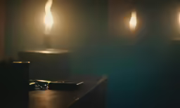 a dark room with lit candles and a cell phone on the table