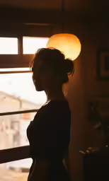 the woman is standing in the dark next to the window