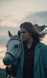 a woman holds a horse, with the sky in the background