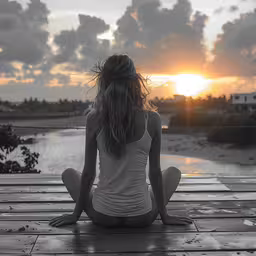 a woman in white sitting on a dock with her head turned backwards,there is a woman sitting on the pier by the water