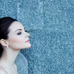 a woman in an evening dress leaning up against a wall with her head resting on a stone