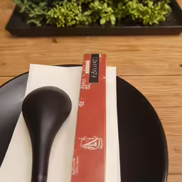 a black plastic fork on a table with a paper napkin