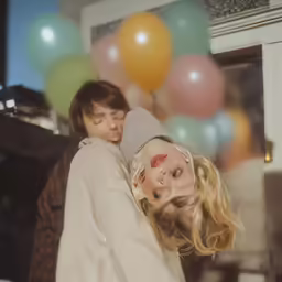 two people that are standing next to some balloons