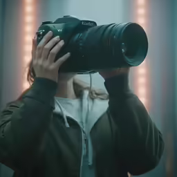 a woman holding a camera in front of a mirror