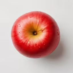 an apple with yellow spot in center sitting on white table