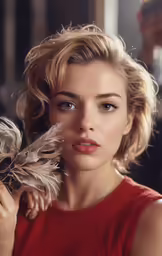 a woman in a red top is holding a feather
