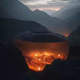a lit object on top of rocks near mountains
