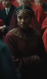 a woman in a red dress with other people behind her