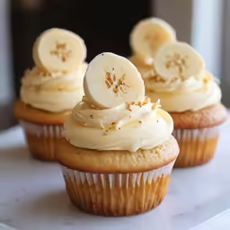 a white plate topped with banana cupcakes and whipped cream