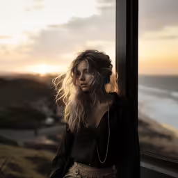 a woman looks out an open window overlooking the ocean,the woman looks out a window at the ocean