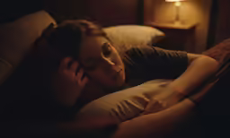 a woman in bed and talking on a cellphone