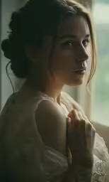 a beautiful woman posing near a window in white