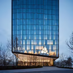 glass building with light reflecting on it and tree lined street