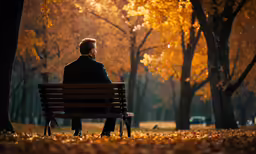 a man in suit and tie sitting on bench in the park