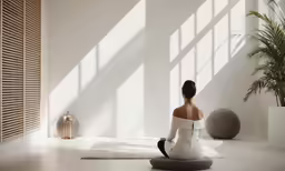 a woman is sitting on the floor in a room with large windows