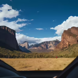 a view from a car driving towards mountains and trees