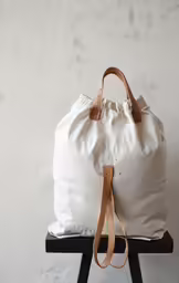 a white duffle bag on a stool