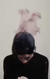 a woman with her head covered by smoke using her cell phone