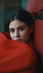 a young lady laying on a chair with a red blanket