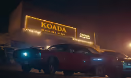 a car parked in front of a kodak sign with lights on
