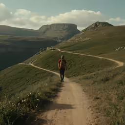the man is walking up the dirt trail to go down