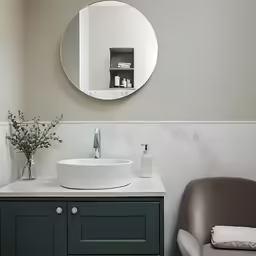 a white sink sitting under a round mirror in a bathroom