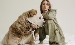 a woman sitting on top of a bed next to a dog
