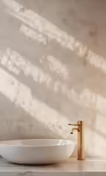 an oval bathroom bowl with golden faucet sitting on the counter