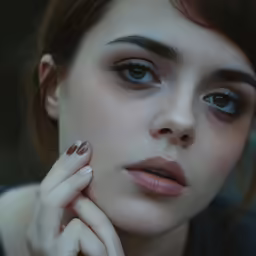 woman with eyeliners and nails is staring at the camera