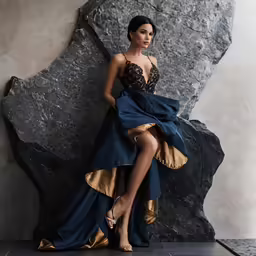 the woman is posing for the camera while in front of the rock
