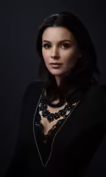 a woman wearing a black dress and long necklace