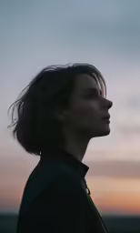 the woman is standing against the sky with her head tilted