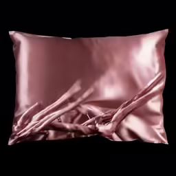a pillow is shown with silky pink sheets