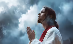 woman in white robe holding hands in front of a cloudy sky
