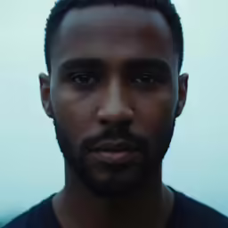 this photo depicts the face and shoulders of a man with short black hair