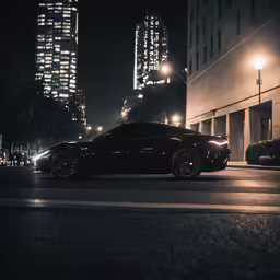 a black car sitting in front of a tall building at night