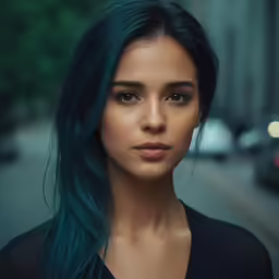 a woman with long dark blue hair with a black top on