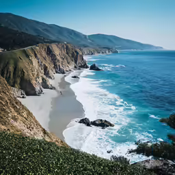 a beach near an ocean next to some hills