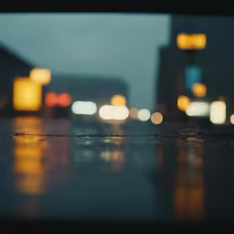 blurry city lights in the evening with a rainy ground
