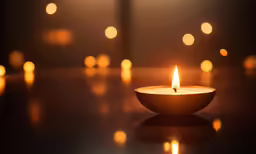 a lit candle sits in front of a wall with lights
