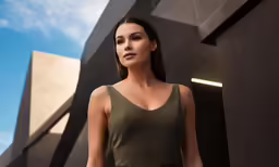 an attractive woman in a green dress standing in front of a building