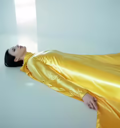 a woman laying down on the floor in a shiny yellow dress