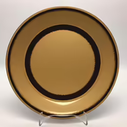 a gold plate on a glass holder against a white background