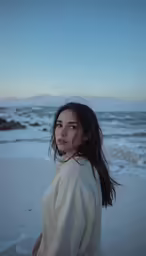 a woman in a white sweater at the beach
